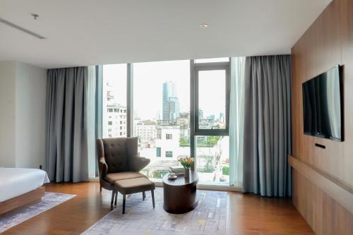 a hotel room with a bed and a chair and a window at Signature by M Village Lê Thánh Tôn in Ho Chi Minh City