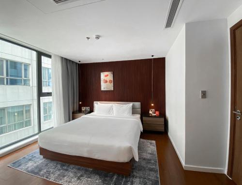 a bedroom with a white bed and a large window at Signature by M Village Lê Thánh Tôn in Ho Chi Minh City