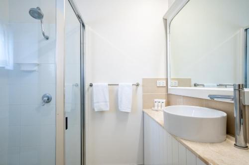 a bathroom with a sink and a glass shower at The Marco Polo in Mackay