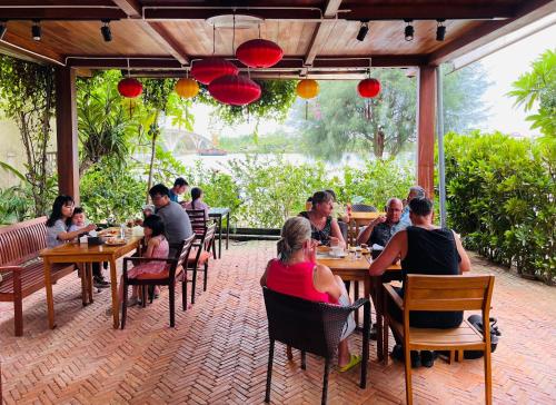 un grupo de personas sentadas en mesas en un restaurante en Villa Orchid Garden Riverside, en Hoi An