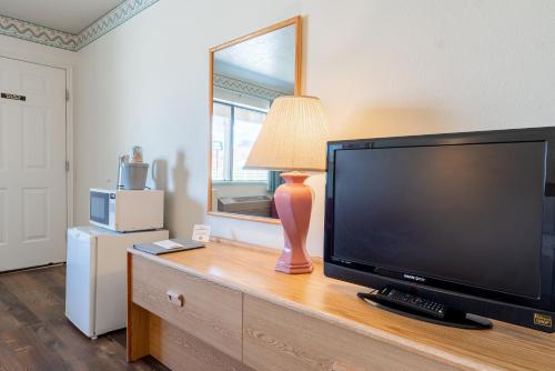 a television on a dresser with a lamp and a mirror at Motel Torrey in Torrey