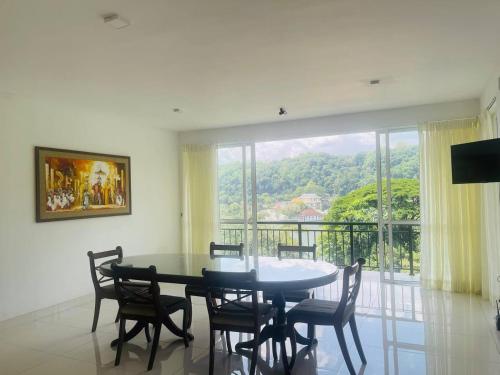 a dining room with a table and chairs and a large window at The Glen Kandy in Kandy