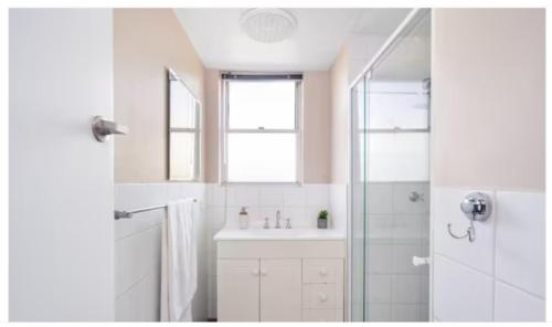 a white bathroom with a sink and a shower at Kalgoorlie Central Accommodation in Kalgoorlie