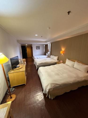 a hotel room with two beds and a television at Hermes Hotel in Hsinchu City