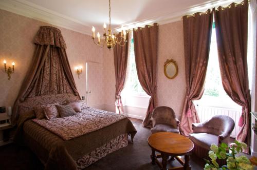 a bedroom with a bed and two chairs and a table at Château de Challanges in Beaune