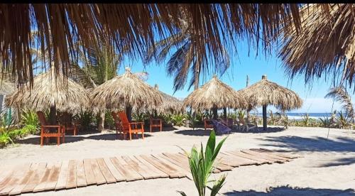 a beach with straw umbrellas and chairs on the sand at QUINTA DIAMANTE villas&hotel in Barra Vieja