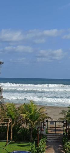 a beach with waves and palm trees and a wooden pathway at QUINTA DIAMANTE villas&hotel in Barra Vieja