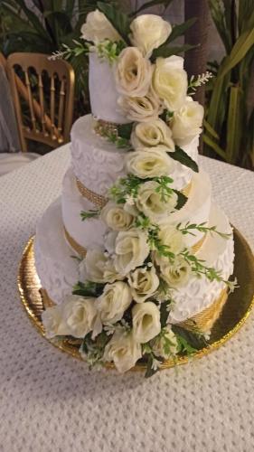 a wedding cake with white roses on a table at QUINTA DIAMANTE villas&hotel in Barra Vieja