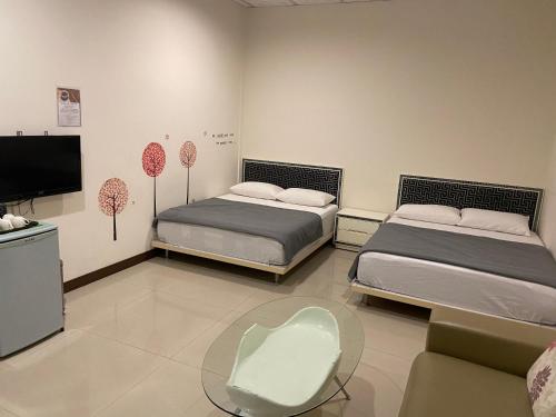 Cette chambre comprend 2 lits, une table et une télévision. dans l'établissement 日升咖啡民宿, à Gukeng