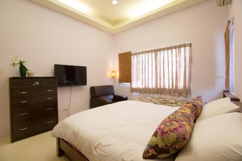 a bedroom with a bed and a television and a chair at Squirrel House in Guanshan