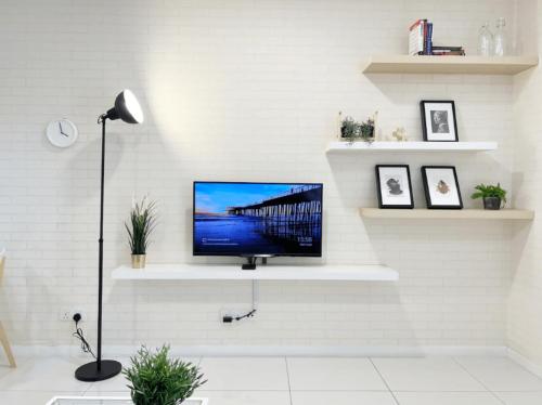 a living room with a tv on a white wall at Mercu Summer Suite Kuala Lumpur in Kuala Lumpur