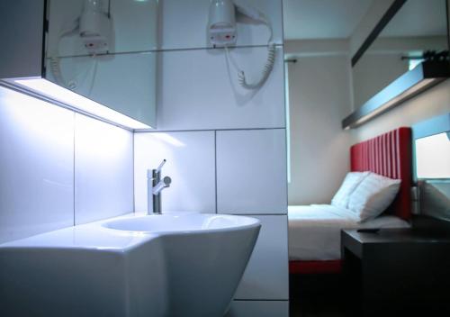 - une salle de bains blanche pourvue d'un lavabo et d'un lit dans l'établissement Hotel Pi Ipoh, à Ipoh
