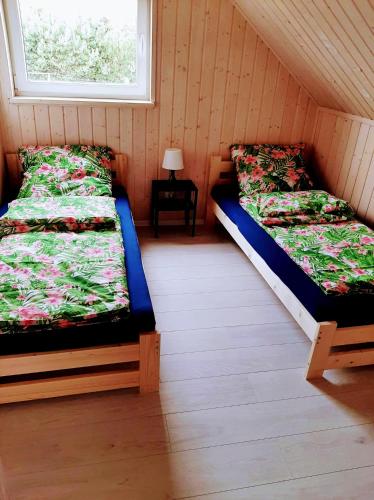 two beds in a room with a window at Domki Poczekajka in Sasino