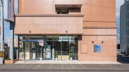 a building with glass doors on a city street at Toyoko Inn Meitetsu Chiryu Ekimae in Chiryu