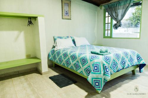 a bedroom with a bed with a colorful comforter and a window at Finca San Alejandro in Cotacachi