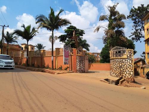 a car driving down a dirt road with palm trees at Sydney Hotel Kampala in Kampala