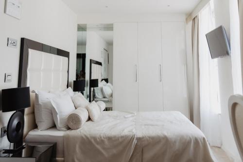 a white bedroom with a large bed with white pillows at Luxury Hotel Amabilis in Selce