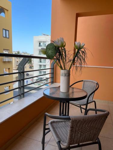 ラルナカにあるVIP Resort Apartment on Makenzie Beachの花瓶付きのバルコニー(テーブル、椅子付)