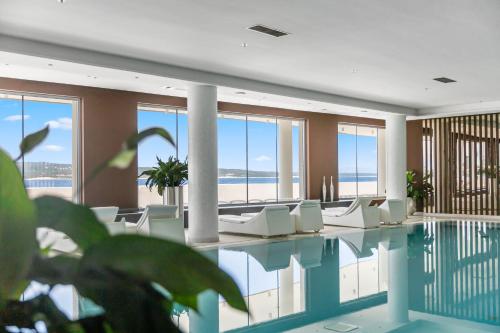 uma piscina com cadeiras brancas e o oceano em Luxury Hotel Amabilis em Selce