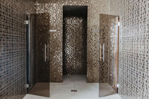 a bathroom with two stalls with brown tiled walls at Luxury Hotel Amabilis in Selce