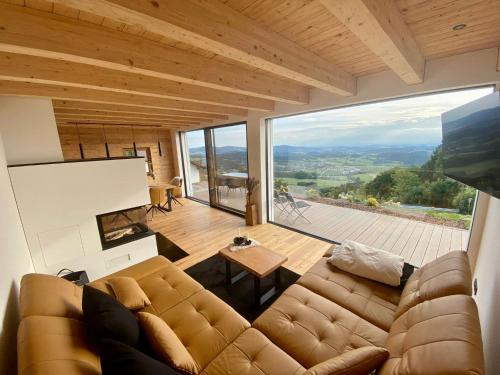 a living room with a couch and a large window at BergChaletWeitblick in Grainet