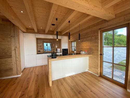 une cuisine ouverte avec des plafonds en bois et une grande fenêtre dans l'établissement BergChaletWeitblick, à Grainet