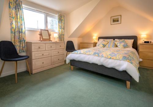 a bedroom with a bed and a dresser and a window at Sunnydale in Llanbedrog