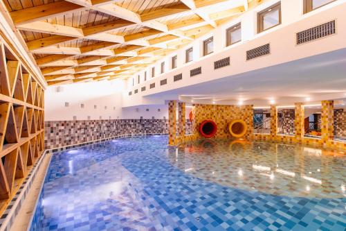 a swimming pool in a large building with wooden ceilings at HOTEL CRYSTAL WELLNESS & SPA superior in Sovata