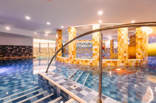 - une piscine revêtue de carrelage jaune et bleu dans l'établissement HOTEL CRYSTAL WELLNESS & SPA superior, à Sovata