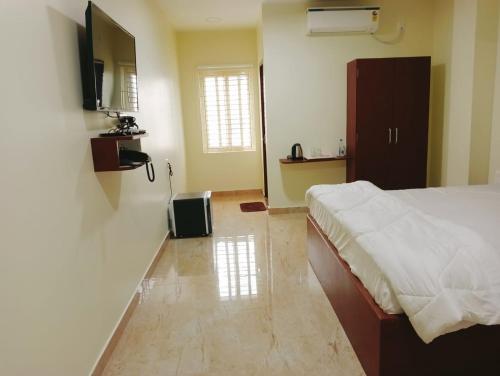 a bedroom with a bed and a television on the wall at The Paradise Guest Inn in Nellore
