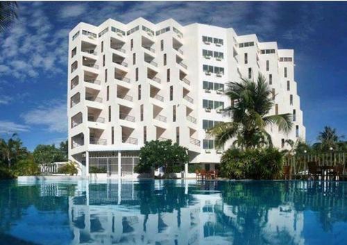 um grande edifício branco com uma piscina em frente em Sea Sand Sun Resort em Rayong