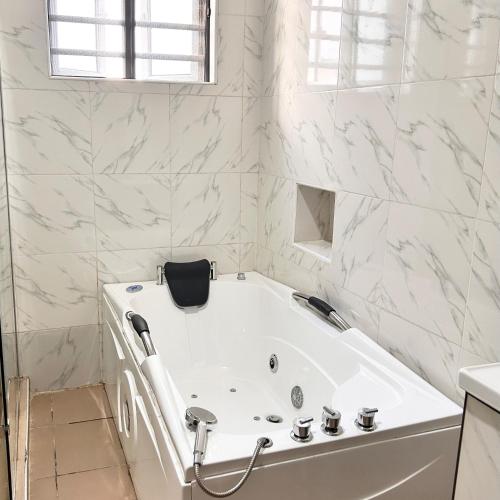a white bath tub in a bathroom with white marble walls at Luxury Shortlet Apartment Ajah, Lekki Lagos in Lagos