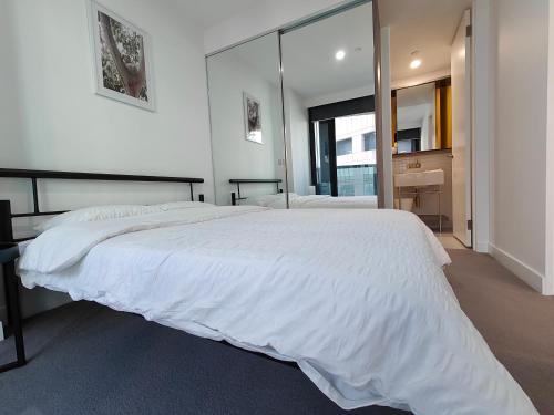 - une chambre avec un grand lit blanc et un grand miroir dans l'établissement Swanston Central 17, à Melbourne