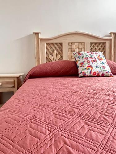 Una cama con un edredón rosa y una almohada. en Casa Alcalde Alojamiento centro Guadalajara en Guadalajara
