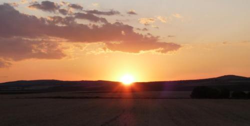 a sunset in a field with the sun setting at Eco Hotel Boutique & Spa Capitulo Trece - Adults Only in Maderuelo