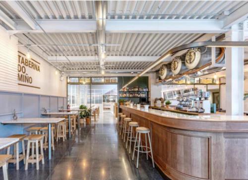 a restaurant with a bar and tables and stools at Apartamentos Forum Ceao in Lugo