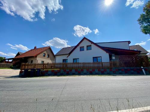 a white house with a wooden fence next to a street at Chalupa Vlasta in Kadov