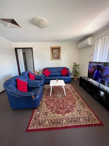 ein Wohnzimmer mit einem blauen Sofa und einem Tisch in der Unterkunft Piccadilly Accommodation in Kalgoorlie