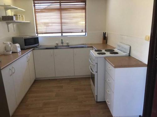 a small kitchen with a stove and a sink at Piccadilly Accommodation in Kalgoorlie