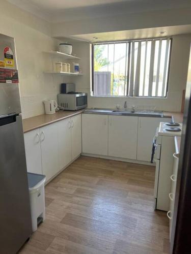 eine Küche mit weißen Schränken und einem großen Fenster in der Unterkunft Piccadilly Accommodation in Kalgoorlie