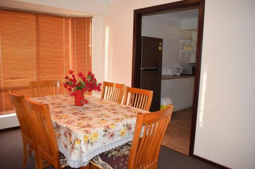 a dining room table with a vase of flowers on it at Piccadilly Accommodation in Kalgoorlie