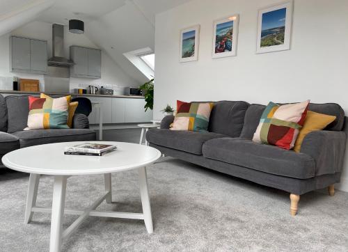 a living room with two couches and a table at Stunning Penthouse in Penzance "Amazing Sea Views" in Penzance