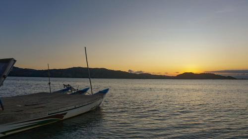 a boat sitting on the water at sunset at Bleu MATHIS Gili Asahan in Gili Asahan