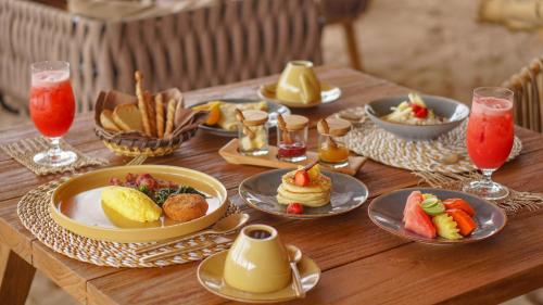 a wooden table topped with plates of food and drinks at Bleu MATHIS Gili Asahan in Gili Asahan