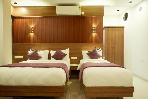 a bedroom with two beds and a wall with a tv at VOVO PREMIER HOTEL in Bengaluru