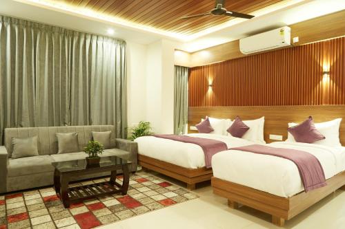 VOVO PREMIER HOTEL في بانغالور: غرفة فندقية بسريرين واريكة