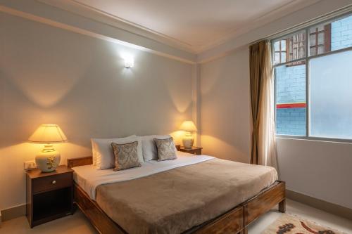 1 dormitorio con 1 cama con 2 lámparas y una ventana en StayVista's Mystic Nest - Mountain & Valley-View Apartment with Contemporary Interiors & Modern Amenities en Gangtok