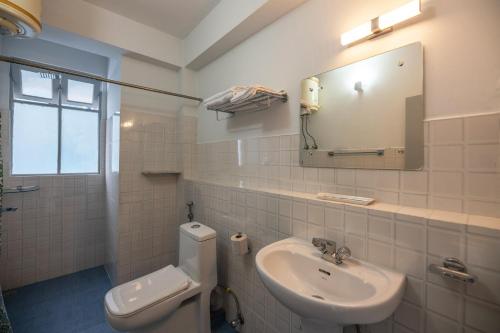 ein Badezimmer mit einem Waschbecken, einem WC und einem Spiegel in der Unterkunft StayVista's Mystic Nest - Mountain & Valley-View Apartment with Contemporary Interiors & Modern Amenities in Gangtok