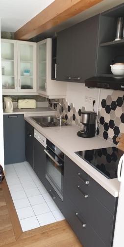 une cuisine avec des armoires noires et blanches et un évier dans l'établissement Appartement 10 couchages face à la meije, à La Grave