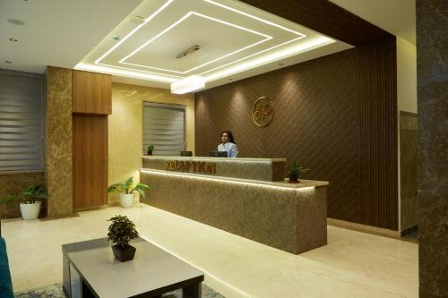 a woman standing at a reception desk in a lobby at VOVO PREMIER HOTEL in Bengaluru